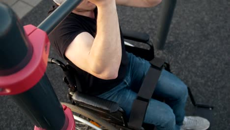 Muscular-disabled-man-in-wheelchair-pulls-up-on-the-crossbar-outdoors