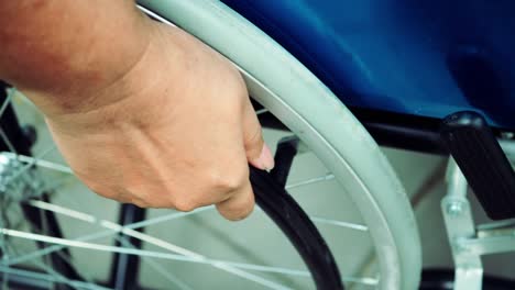 Close-up-Hand-mit-Rollstuhl-Patienten-alleine-fahren