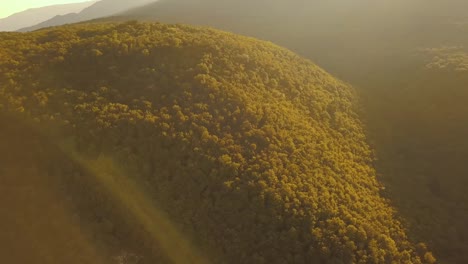 Luftbild-Drohnenflug-über-die-Felskante-Berg-hoch-oben-mit-Sonnenuntergang-massive-Wald