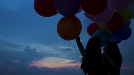 Young-couple-people-holding-balloon-with-sunset-background-in-slow-motion.