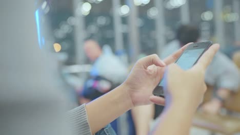 Asian-woman-using-smartphone-while-sitting-in-international-airport.