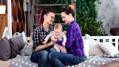 Two-young-informal-girl-enjoying-motherhood-holding-little-baby-girl-medium-long-shot