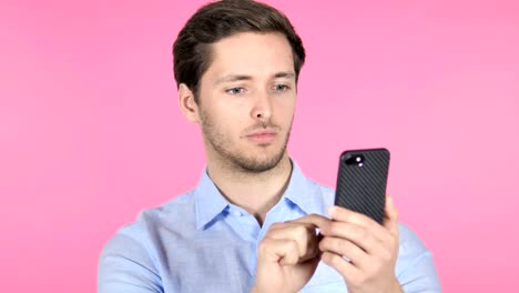 Young-Man-Using-Smartphone-on-Pink-Background