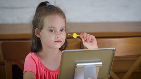 hermosa-niña-comiendo-helado-y-viendo-la-caricatura-en-la-tableta