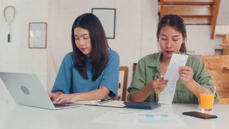 Business-Asian-Lesbian-couple-using-calculator-record-budget,-tax,-financial-document-on-laptop-working-in-kitchen.