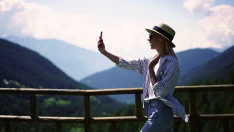 Excited-caucasian-female-tourist-using-roaming-network-connection-during-trip-to-mountains-making-video-call