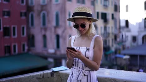 Slow-motion-effect-of-happy-female-tourist-dressed-in-trendy-apparel-using-cellular-phone-for-messaging-with-followers-from-own-travel-blog