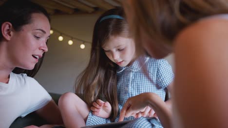 GleichGeschlecht-weibliche-paar-sitzen-auf-dem-Bett-mit-Tochter-zu-Hause-zusammen-mit-digitalen-Tablet