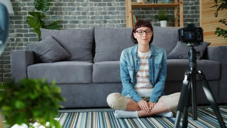 Cheerful-woman-in-glasses-is-speaking-and-gesturing-recording-video-at-home