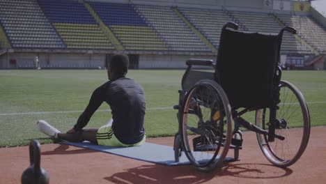 Athlete-sitting-on-ground-and-warming-up