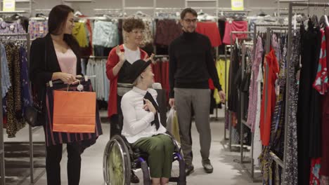 Mujer-feliz-en-silla-de-ruedas-y-sus-amigos-comprando-ropa