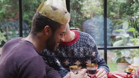 Pareja-masculina-gay-sentada-alrededor-de-la-mesa-para-la-cena-de-Navidad-hablando-y-haciendo-un-brindis