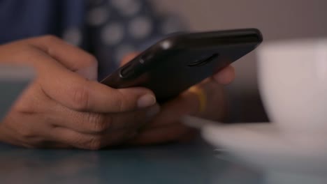 Mujer-usando-teléfono-inteligente-en-el-escritorio-en-casa.