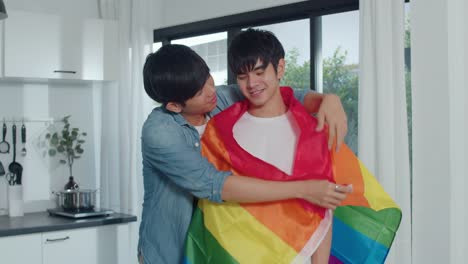 Asian-Gay-couple-standing-and-hugging-room-at-home.-Young-handsome-LGBTQ+-men-kissing-happy-relax-rest-together-spend-romantic-time-in-modern-kitchen-with-rainbow-flag-at-house-in-the-morning-concept.