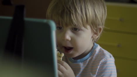 little-boy-eating-while-watching-digital-tablet