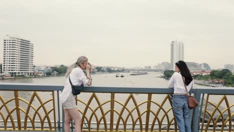 Two-girls-Asian-lesbian-couples-enjoying-traveling-in-Thailand-and-using-a-film-camera-taking-a-photo.-Beautiful-young-women-having-fun-in-vacation-time.-LGBT-concept.