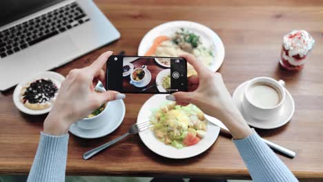 POV-disparó-manos-femeninas-fotografiando-alimentos-en-la-mesa-usando-el-teléfono-inteligente.-Disparo-de-cerca-en-la-cámara-4k-RED