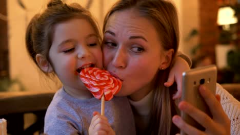 Tochter-mit-Mama-machen-Selfie-essen-herzförmige-Süßigkeiten