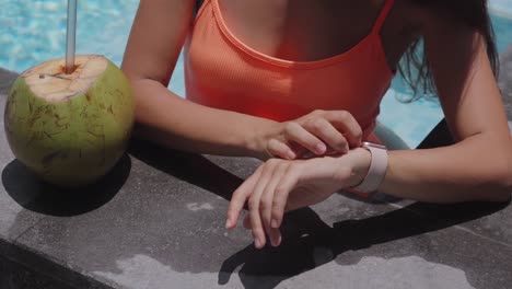 Hands-of-an-active-young-woman-touching-the-screen-of-a-smartwatch-in-pool