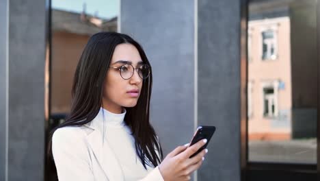 Zuversichtliche-Geschäftsfrau-zu-Fuß-im-Freien-chatten-verwenden-Smartphone.-Nahaufnahme-auf-4k-RED-Kamera