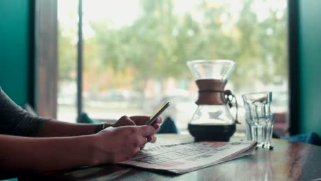 Primer-plano-de-manos-femeninas-imprimir-sms-en-su-teléfono-móvil-en-un-café