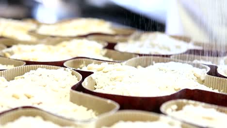 manos-de-chef-de-repostería-azúcar-en-polvo-por-aspersión-en-masa-para-las-palomas-de-la-torta-de-Pascua