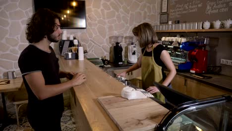 Man-entering-a-coffee-shop-and-ordering-a-cappuccino-to-go-and-then-paying-it-with-mobile-app-crypto-currency-bitcoin