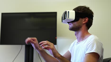 Young-man-with-VR-virtual-reality-headset-goggles-on-his-head-in-business-office.