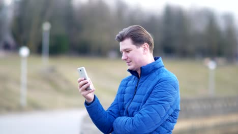 A-young-attractive-man-is-using-a-mobile-phone-at-sunset.