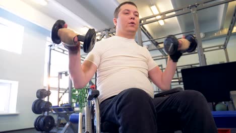 Disabled-athlete-in-a-wheelchair-strengths-his-hands-via-dumbbells.