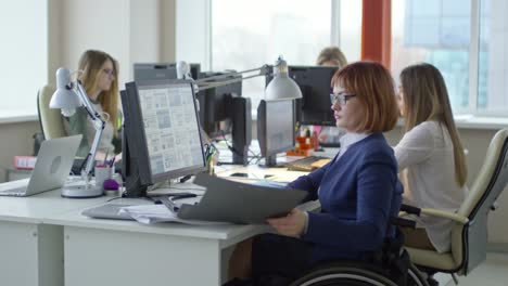 Empresaria-parapléjico-en-silla-de-ruedas-trabajando-en-escritorio-en-la-oficina