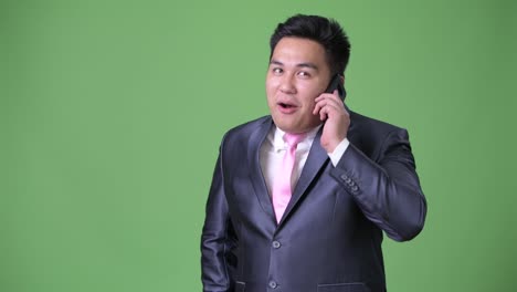 Young-handsome-overweight-Asian-businessman-against-green-background