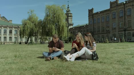 Lächelnde-Studenten-Vernetzung-mit-Smartphones-auf-Rasen