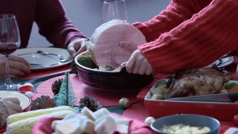 Mano-sosteniendo-tocino-grande-en-la-bandeja-colocada-en-la-mesa-para-la-cena-el-día-de-Navidad