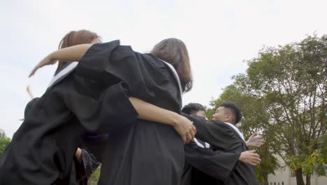 glückliche-Studenten-in-Abschlusskleidern-mit-Diplomen-auf-dem-Universitätscampus