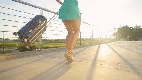 BAJO-ANGLE:-La-mujer-feliz-gira-con-su-maleta-mientras-camina-hacia-el-aeropuerto.