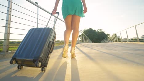 LOW-ANGLE:-Junge-Frau-schleppt-ihren-Koffer-zum-Flughafen-in-ihren-High-Heels