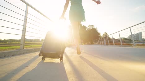 ANGLE-BAJO:-Una-mujer-joven-con-tacones-salta-mientras-camina-hacia-el-aeropuerto-al-atardecer