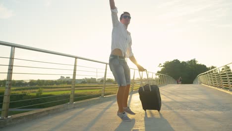 LENS-FLARE-Cheerful-guy-clicks-his-heels-while-walking-to-the-airport-at-sunrise