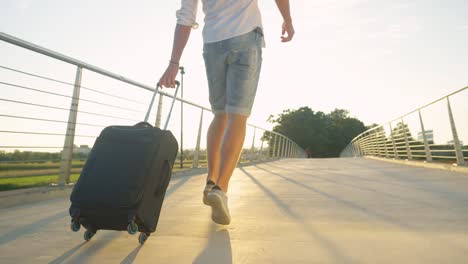 LOW-ANGLE:-Excited-man-clicks-his-heels-while-walking-to-the-airport-at-sunset.