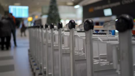 Row-of-luggage-carts-at-airport-terminal,-airport-baggage-trolley-parking-lot