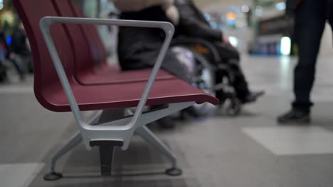 Mochila-de-viaje-en-el-banco-en-la-zona-de-espera-de-la-terminal-del-aeropuerto-con-sillas