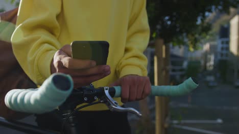 Adulto-transgénero-con-una-bicicleta-y-el-uso-de-un-teléfono