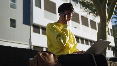 Transgender-adult-using-phone-and-laptop-in-the-street