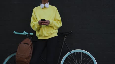 Adulto-transgénero-con-una-bicicleta-y-el-uso-de-un-teléfono