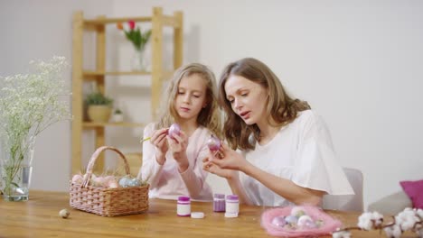 Madre-e-hija-poniendo-pintura-de-brillo-en-los-huevos-de-Pascua