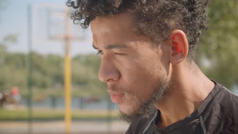 Closeup-portrait-of-young-handsome-african-american-male-basketball-player-being-determined-sitting-outdoors