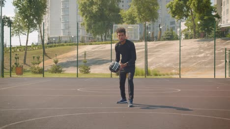 Primer-plano-frente-retrato-de-joven-atractivo-jugador-de-baloncesto-afroamericano-masculino-lanzando-una-pelota-en-un-aro-al-aire-libre-en-la-cancha