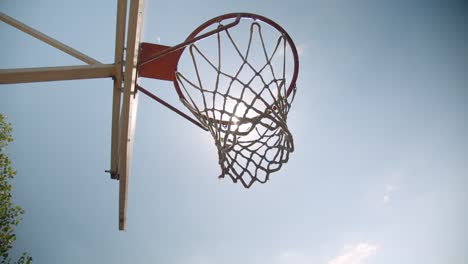 Nahaufnahme-Porträt-von-Basketballball-in-einen-Reifen-im-Freien-auf-dem-Platz-mit-hellem-Sonnenlicht-geworfen