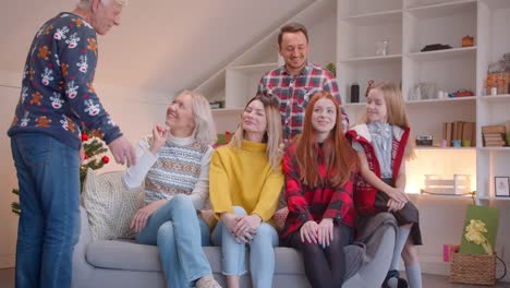 Gran-familia-se-está-preparando-para-un-retrato-en-el-sofá-de-Navidad-aplaudiendo-sonriendo-feliz